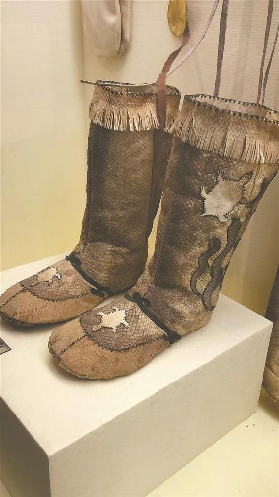 A pair of traditional Hezhe high boots displayed in a museum case